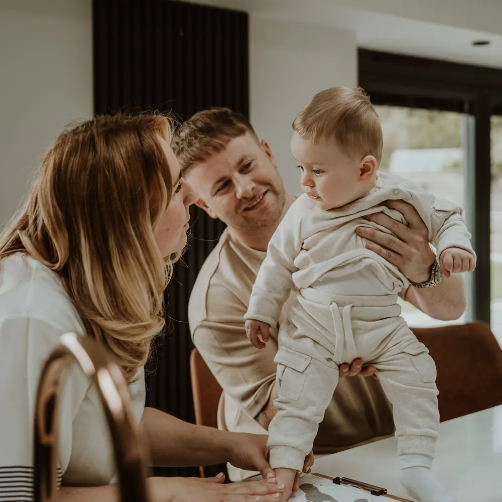 Parents holding their baby while taking a foil keepsake footprint at a Memory Catcher session